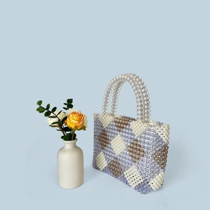 Detail of handmade woven beaded tote bag featuring a geometric diamond pattern in light blue