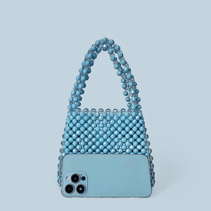 Blue beaded handmade handbag showing capacity by holding a smartphone inside