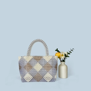 Detail of a handmade beaded handbag with a geometric diamond pattern and a beaded handle