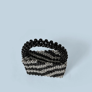 Macro detail of handmade beaded bucket bag with black and silver wave pattern textures