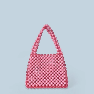 Detailed view of hand-woven pink acrylic beadwork and vintage style handle on a handbag