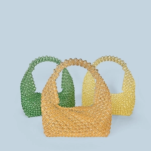 Detailed close-up of handmade beaded tote bags in emerald green, amber, and yellow