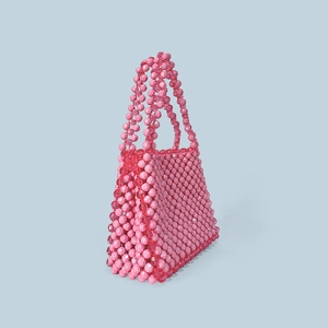 Detail view of pink and translucent red beaded handmade handbag from a side angle