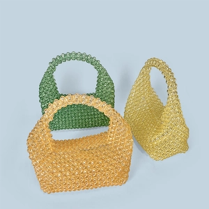 Detail of handcrafted beaded mini tote bags in green, amber, and yellow acrylic weave