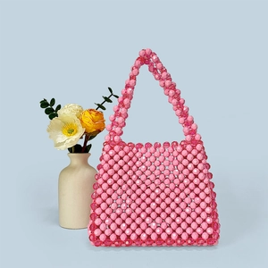 Close-up of pink handmade beaded handbag with smooth glossy texture on blue background