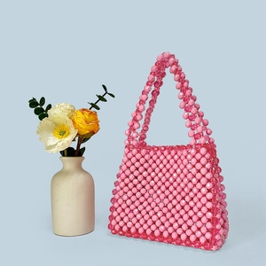 Close-up of handmade pink beaded handbag with detailed woven texture on blue background