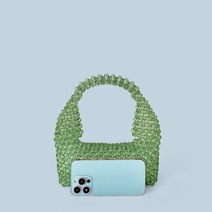 Detailed view of mini handmade green beaded tote bag with smartphone for size reference