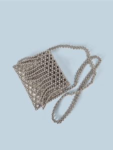 Detail of handcrafted silver beaded crossbody bag featuring a woven metallic texture