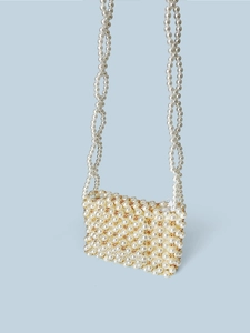 Détail du mini sac perlé fait main avec accents dorés et bandoulière tissée