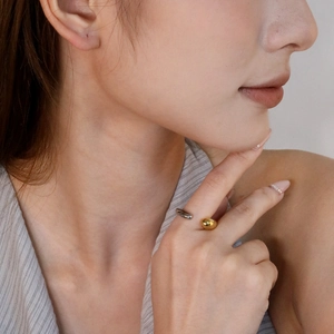 Détail d'une bague ajustable bicolore argent et or avec perle métallique sur une main