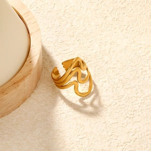 Detail eines vergoldeten Wellenrings mit minimalistischen Kurven auf strukturiertem Grund