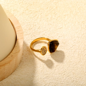 Détail d'une bague dorée avec pierre œil de tigre et pavage de zircons brillants