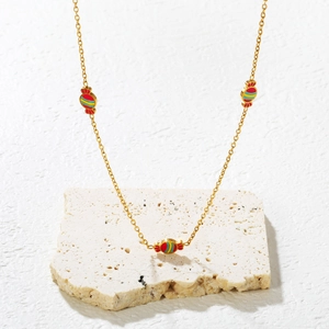 Golden necklace set with three colorful candy-shaped pendants on white marble surface
