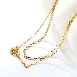 Collier double épaisseur en or avec pendentif raquette de tennis sur un fond blanc