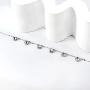 Close-up of silver anklet featuring six round white cubic zirconia stones in bezel settings