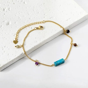 Detail of gold stainless steel anklet with colorful beads and turquoise stone bar on marble