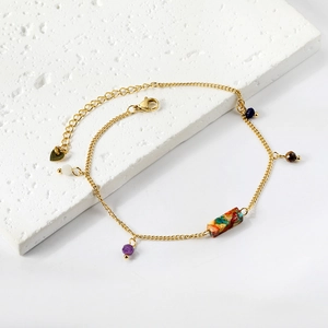 Detail of gold stainless steel anklet with colorful stone pendants and heart charm