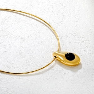 Collana minimalista con ciondolo a goccia dorata con intarsio nero su catena a serpente