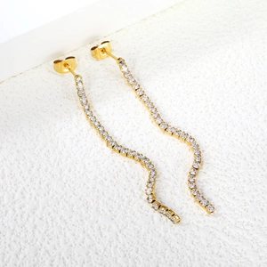 Macro shot of long gold-plated wavy tassel earrings featuring sparkling zircon inlay details