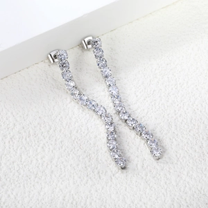 Macro shot of silver tassel earrings with round cubic zirconia on a white pedestal