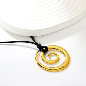 Collier minimaliste avec pendentif spirale doré et cordon ciré noir sur plateau blanc