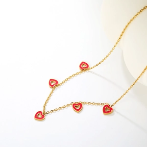 Close-up of golden necklace featuring five vibrant red enamel hollow heart pendants