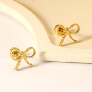 Boucles d'oreilles nœuds dorées avec texture torsadée sur plateau esthétique beige