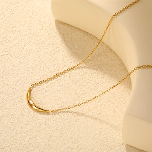 Elegant gold curved moon necklace with white cat eye stone on minimalist display