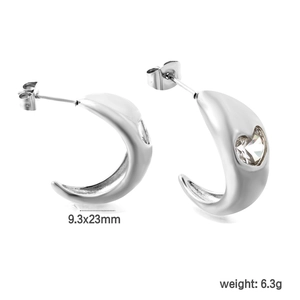 Macro detail of silver C-shaped earrings with heart-cut crystals on white background