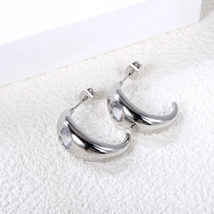 Detailed close-up of silver C-shaped moon earrings with sparkling heart-cut white zircons
