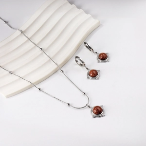 Détail d'une parure vintage en grès rouge avec collier et boucles d'oreilles sur blanc