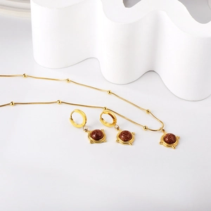 Détail de l'ensemble de bijoux en acier doré avec grès brun et collier chaîne serpent