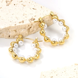 Elegante Creolen mit 18K Goldbeschichtung und weißen Perlen auf Naturstein-Hintergrund