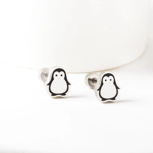 Macro detail of penguin stud earrings with black and white enamel and silver finish