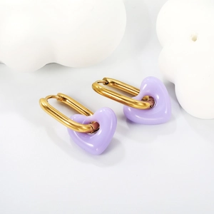 Pendientes de corazón morado con aros dorados sobre fondo blanco decorativo