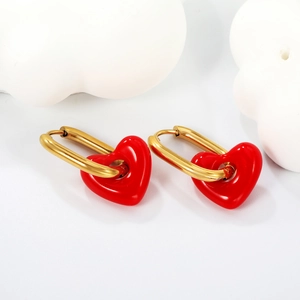 Detalle de corazones de resina roja en pendientes de acero inoxidable dorado en fondo blanco