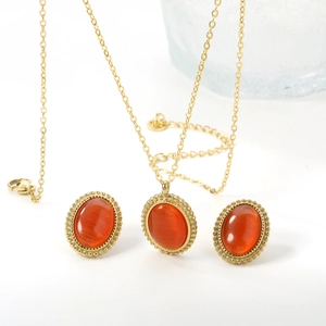 Macro detail of gold necklace and earrings set featuring oval orange cat-eye stones