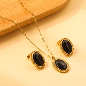 Macro view of gold-plated oval black stone pendant and earrings with beaded edges