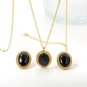 Detailed view of oval black stone necklace and earrings with gold milgrain edges