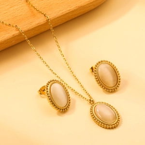 Close-up of gold stainless steel jewelry set with oval opals and beaded edges