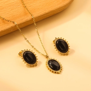 Detail of vintage gold-plated necklace and earrings set with oval black stones on wood