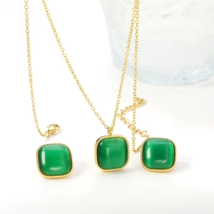 Détail de parure dorée avec pendentifs œil-de-chat verts et bordures de style torsadé
