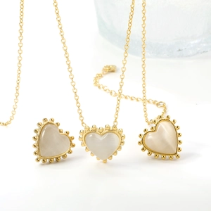 Close-up of golden heart pendant with cat eye stone and vintage beaded edge on O-chain