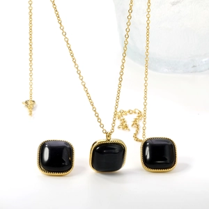 Détail d'une parure collier et boucles d'oreilles dorée avec pierre œil de chat noire