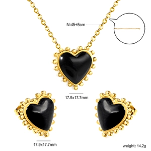 Macro detail of heart-shaped necklace and earrings with beaded gold trim and black inlay
