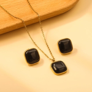 Détail d'un ensemble collier et boucles d'oreilles carrés noirs à bord doré torsadé