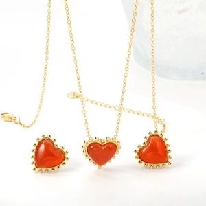 Detailed view of red cat-eye heart jewelry set with gold beaded edges on white base