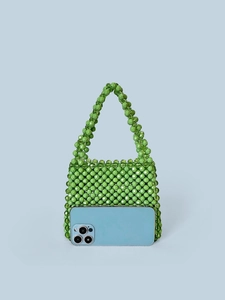 Handmade green beaded handbag with square structure and round handle on blue background