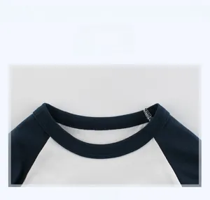 Gros plan des coutures du col contrasté sur le t-shirt raglan enfant bleu marine et blanc