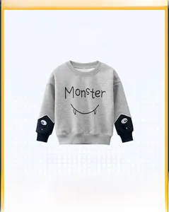 Detailed view of kids' gray sweatshirt with blue contrast cuffs and monster pattern